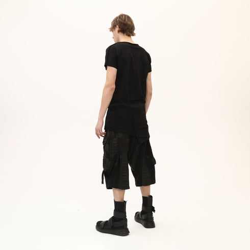 Back angle view of men’s black asymmetric raw seam T-shirt with layered hem construction.