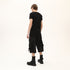 Back angle view of men’s black asymmetric raw seam T-shirt with layered hem construction.
