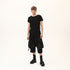 Full styling view of men’s black asymmetric raw seam T-shirt for festival and streetwear outfits.
