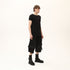 Full styling view of men’s black asymmetric raw seam T-shirt for festival and streetwear outfits.