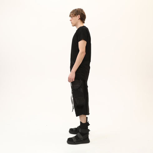 Side profile of men’s black asymmetric raw seam T-shirt showing regular fit and raw edge details.