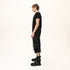 Side profile of men’s black asymmetric raw seam T-shirt showing regular fit and raw edge details.
