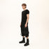 Side view of men’s black asymmetric raw seam T-shirt styled with black statement shorts.