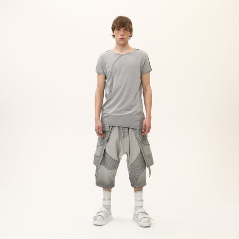Front view of men’s grey asymmetric raw seam T-shirt with uneven hem and avant-garde streetwear styling.