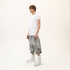 Side view of men’s white asymmetric raw seam T-shirt styled with grey statement shorts.
