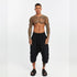 Front view of men’s black paneled drop-crotch capri pants with elastic waistband and relaxed avant-garde silhouette.