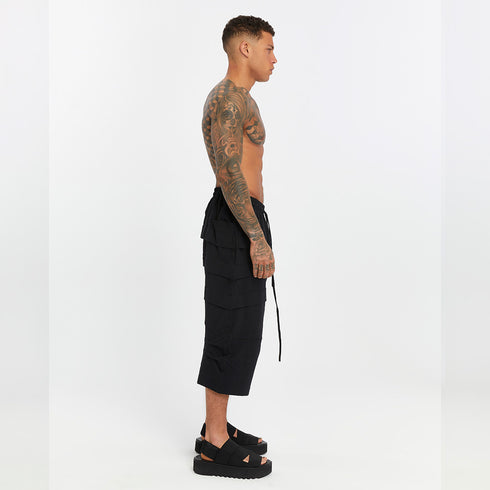 Opposite side view of men’s black drop-crotch capri pants with paneled design and relaxed wide-leg shape.