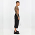 Opposite side view of men’s black drop-crotch capri pants with paneled design and relaxed wide-leg shape.