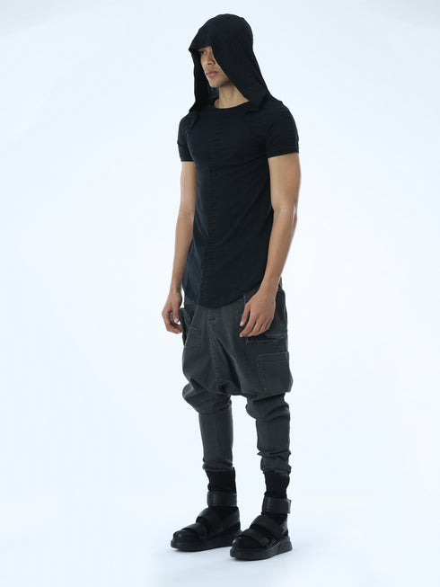 Angle view of men’s black hooded T-shirt showing pleated front detail, shoulder accents and long curved hem.