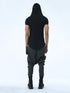 Back view of men’s black hooded multi-pleated T-shirt with long curved hem and bold Junus Coban silhouette.