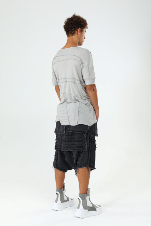 Back angle view of men’s grey paneled T-shirt with raw seam construction and Junus Coban streetwear attitude.