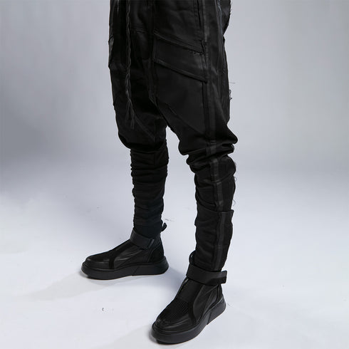 Detail view of men’s black shalwar pants with slim lower-leg shape, seam details and bold streetwear styling.