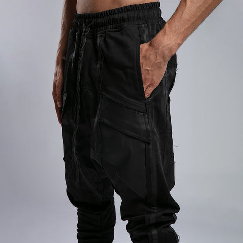 Detail view of men’s black shalwar pants showing side pocket, piped trim and raw stitch construction.