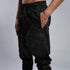 Detail view of men’s black shalwar pants showing side pocket, piped trim and raw stitch construction.