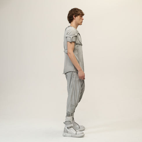 Side styling view of men’s anthracite raw seam T-shirt worn with light drop-crotch pants.